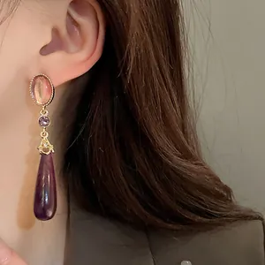 Close-up of vintage teardrop earrings with pink and purple stones on model's ear