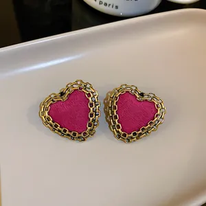 Macro view of pink heart stud earrings with elegant golden chain-link border detail