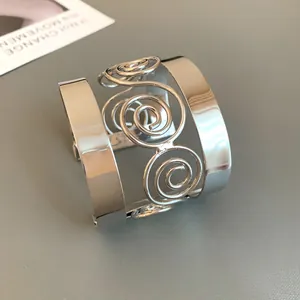 Detailed view of a silver wide cuff bracelet featuring a unique spiral scrollwork design