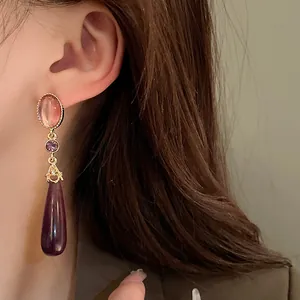 Close-up of vintage royal style teardrop earrings with purple stones on an Asian model.