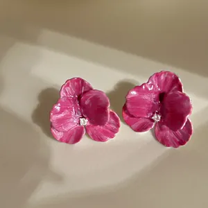 Detailed view of pink floral enamel earrings with a shimmering central crystal accent