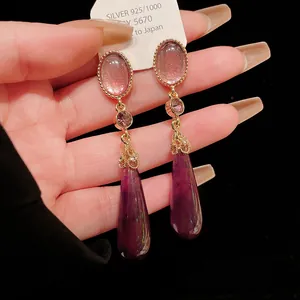 Detailed view of retro palace style waterdrop earrings with purple crystals.