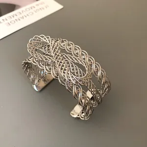 Detailed macro view of an intricate silver-colored woven mesh cuff bracelet