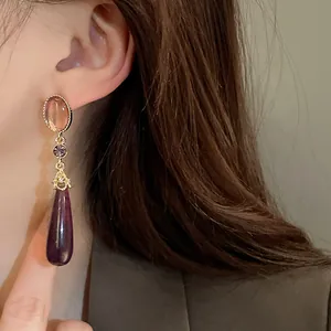 Elegant vintage court style purple teardrop dangle earrings with gold settings worn by model
