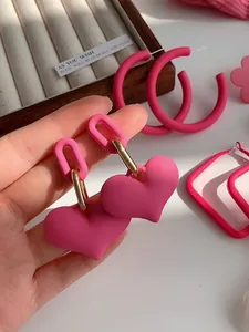 Detailed close-up of vibrant matte pink heart earrings featuring stylish gold link accents