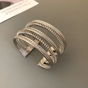 Close-up detail of a silver multi-layer geometric cuff bracelet with twisted design