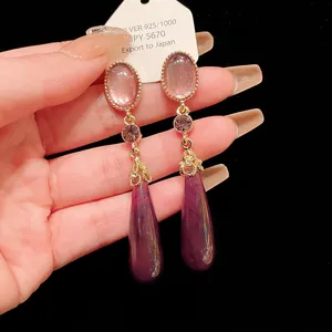Close-up of vintage purple teardrop earrings with 925 silver needle and gold accents