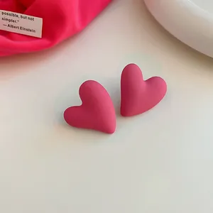 Close-up of matte pink heart-shaped stud earrings with smooth finish