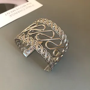 Detail of silver geometric cuff bracelet with hollow wavy pattern and braided edges