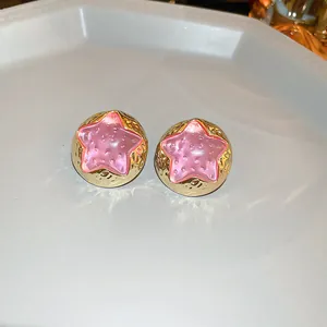 Detailed macro view of gold hammered star earrings with textured pink inlays.