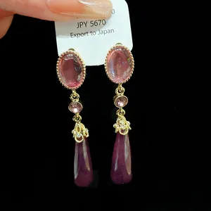 Macro detail of vintage teardrop earrings featuring elegant pink and purple gemstone settings