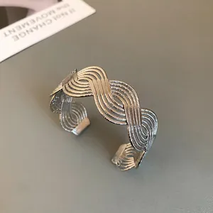 Close-up of silver minimalist wave pattern cuff bracelet with textured metal finish