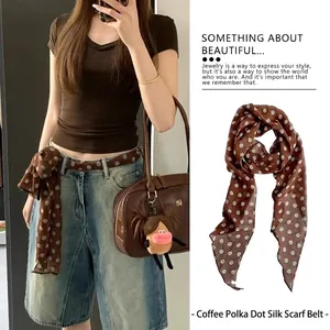 Primo piano di un foulard di seta marrone a pois indossato come cintura su pantaloncini