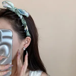 Detailed side view of a vintage floral silk scarf wrapped headband with a large bow