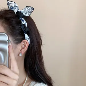 Detailed view of a stylish bow-knot headband with floral pattern fabric worn by a model.