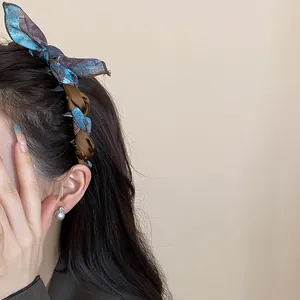 Close-up detail of an elegant Korean silk scarf bow headband styled on dark brown hair
