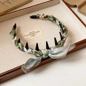 Sage green floral silk scarf wrapped headband with a charming bow detail on a vintage tray