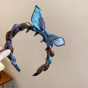 Detailed view of a vintage style fabric wrapped bow headband in blue and brown silk scarf