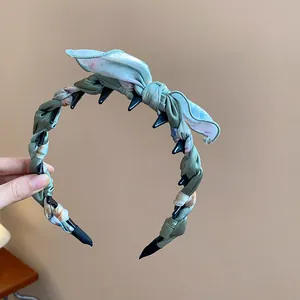 Detailed view of a Korean-style twisted fabric headband with a bow and inner teeth.