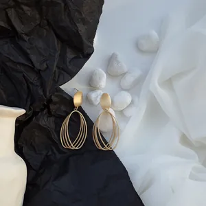 Close-up view of minimalist hollow geometric oval earrings with elegant matte gold finish