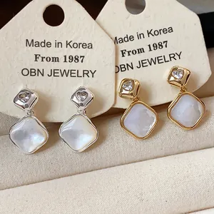 Detail shot of diamond-shaped 18k gold plated clip-on earrings with zircon hearts.