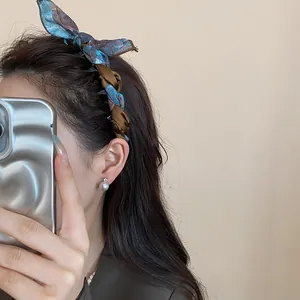 Detailed view of a retro floral silk scarf bow headband on dark brunette wavy hair