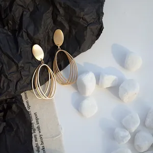 Macro view of matte gold geometric hollow oval earrings on textured background