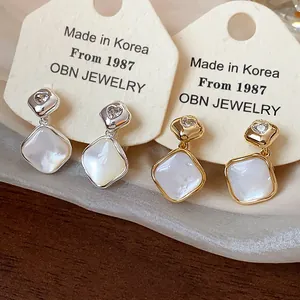 Detail of 18k gold plated diamond-shaped clip earrings in gold and silver finish