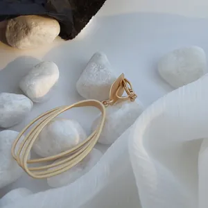 Detailed macro view of matte gold geometric hollow earrings resting on white pebbles