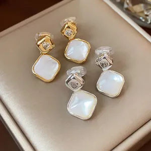 Detail shot of elegant rhombic clip-on earrings in gold and silver with white inlay