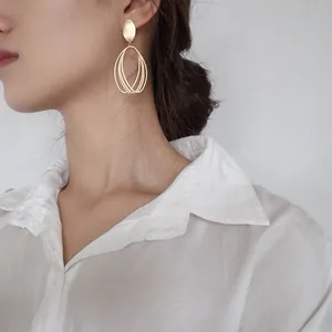 Close-up of minimalist matte gold geometric hollow earrings worn by a model