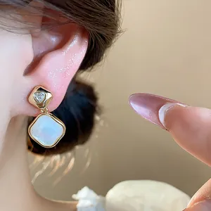 Close-up of 18k gold plated rhombus earring with zircon heart and white inlay