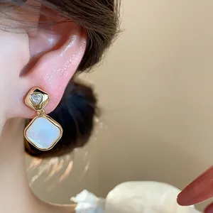 Close-up of 18k gold plated geometric clip-on earring with zircon and white stone