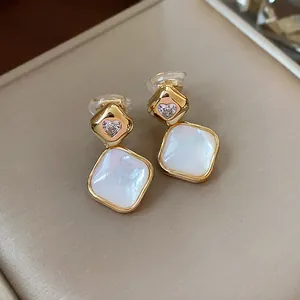 Detailed view of 18k gold plated rhombus ear clips with pink heart stone and white inlay