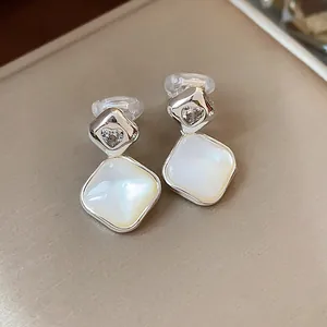 Close-up of elegant rhombus clip-on earrings with heart-shaped zircon and white shell inlay
