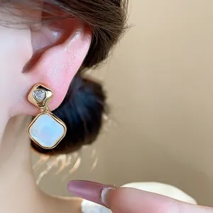 Close-up of 18k gold plated rhombus earring with a heart-shaped zirconia on ear