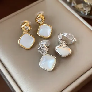Macro view of gold and silver diamond-shaped clip-on earrings with heart zircon