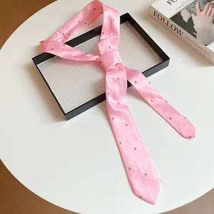 Cintura a sciarpa in seta rosa vintage con motivi delicati su un tavolo bianco minimalista