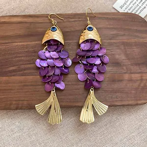 Détail exquis de boucles d'oreilles en forme de poisson avec écailles en nacre violette