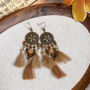 Gros plan de boucles d'oreilles ethniques rétro à pompons marrons et motifs mandala.