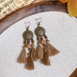 Détail de boucles d'oreilles bohèmes vintage avec accents en bronze et perles.