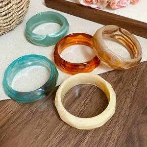 Set of five colorful marbled acrylic bangles with stylish faceted edges on wooden surface