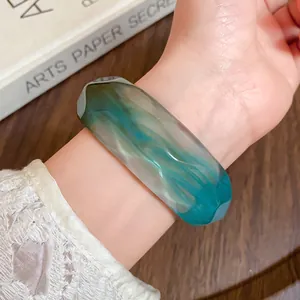 Detailed shot of a faceted acrylic bangle featuring a unique teal marbled texture on a wrist