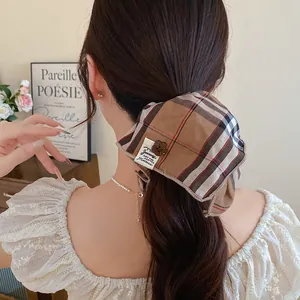 Κοντινό πλάνο καφέ καρό scrunchie σε μια καστανή αλογοουρά