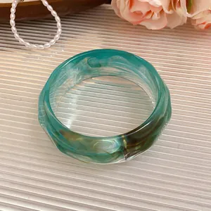 Close-up of a teal marbled acrylic faceted bangle with unique swirls and textures