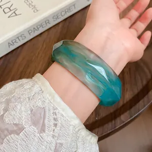 Detail showing a green marbled acrylic faceted bangle bracelet on a woman's wrist
