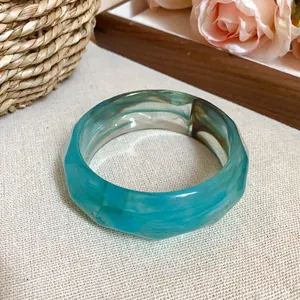 Detail view of a faceted acrylic bangle featuring an elegant blue marble swirl pattern