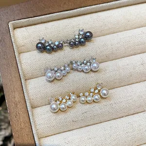 Close-up of elegant curved pearl and zircon stud earrings in gold and silver finishes