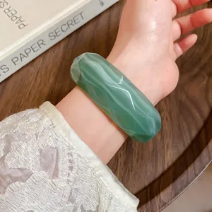 Close-up of green marbled acrylic faceted bangle showing striped texture and polish