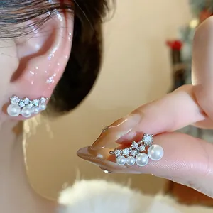 Close-up of elegant curved stud earrings with gradient pearls and sparkling cubic zirconia
